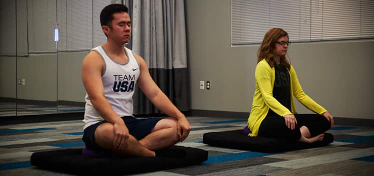 Two people with crossed legs and closed eyes, meditating