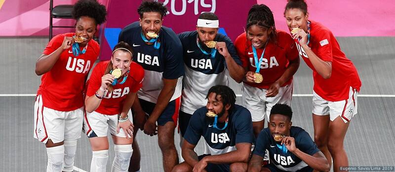 The U.S. men's and women's 3x3 teams celebrate winning as the players bite their gold medals.