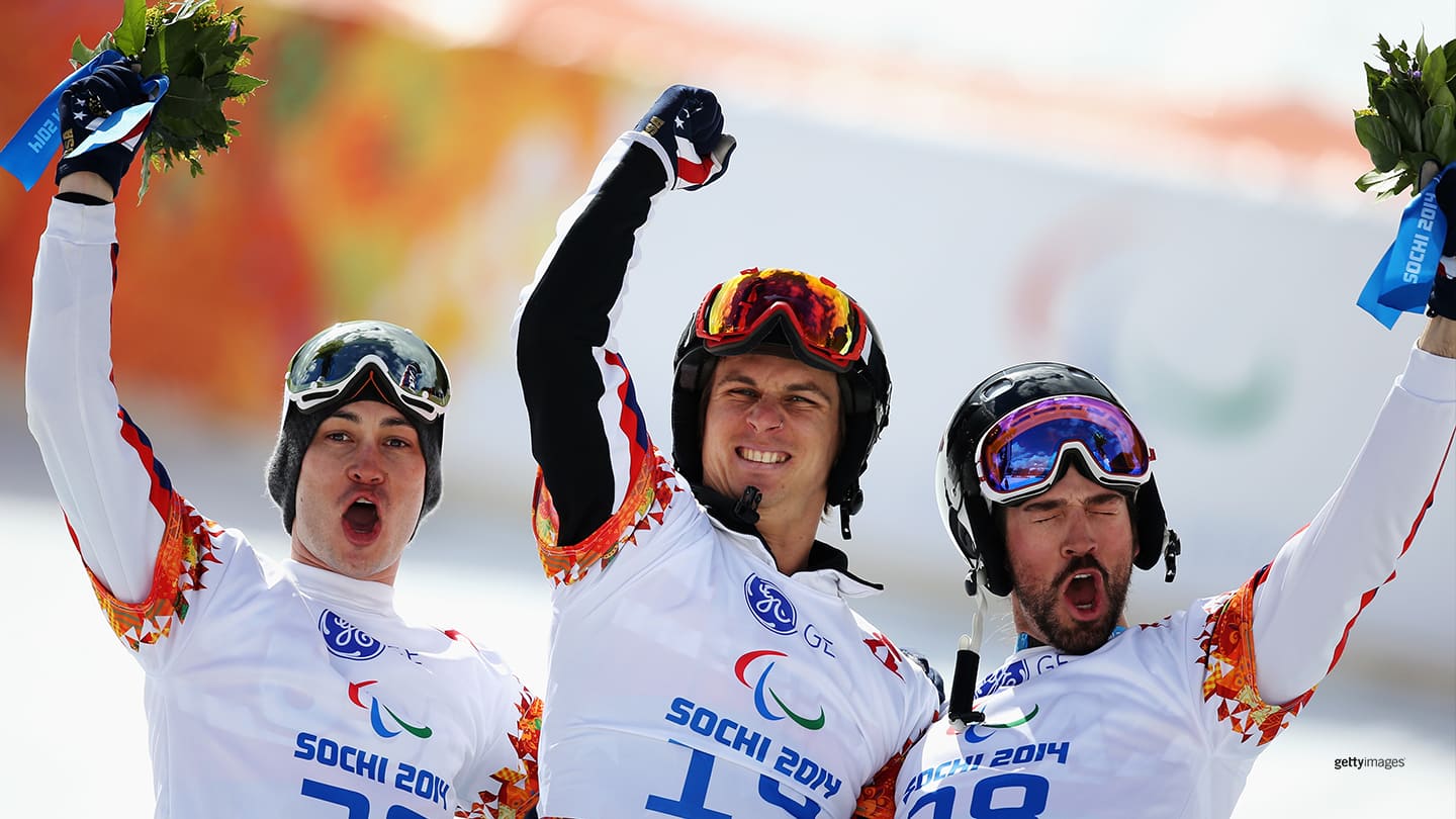 Evan Strong (C) celebrates winning the gold medal with silver medalist Michael Shea (L) and bronze medalist Keith Gabel during the flower ceremony for the Men's Para Snowboard Cross Standing at the Sochi 2014 Paralympic Winter Games on March 14, 2014 in Sochi, Russia. 