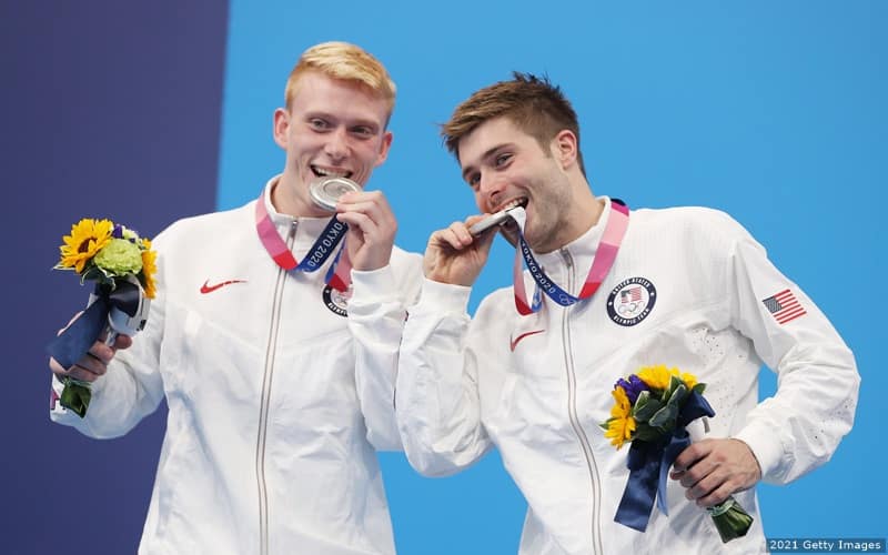 U.S. divers Andrew Capobianco and Michael Hixon take a bite out of their silver medals after earning them in the men's synchronized 3 meter springboard at the 2020 Olympics.  