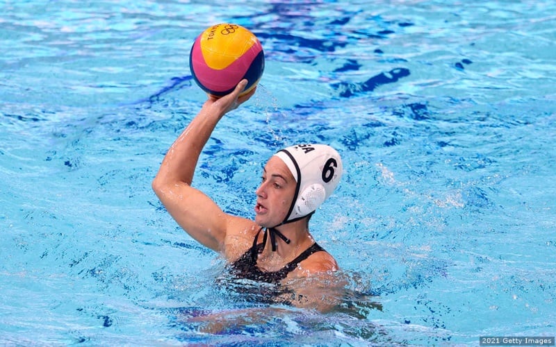 U.S. water polo athlete Margaret Steffens holds the ball aloft in a match against China at the 2020 Olympic Games. 