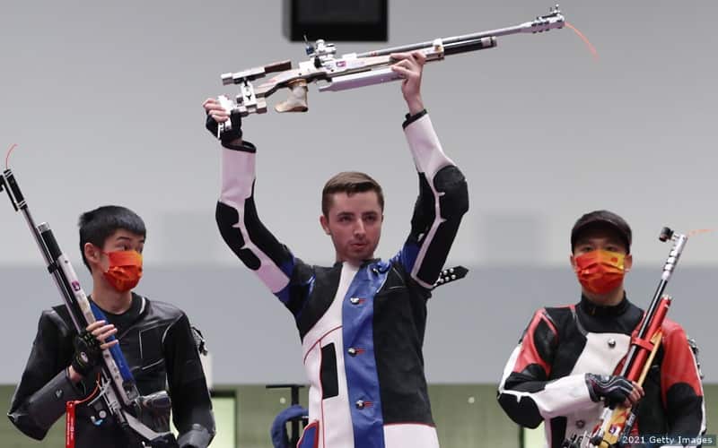Will Shaner holds his rifle aloft after winning gold  in the men's 10m air rifle at the Tokyo 2020 Olympic Games. 