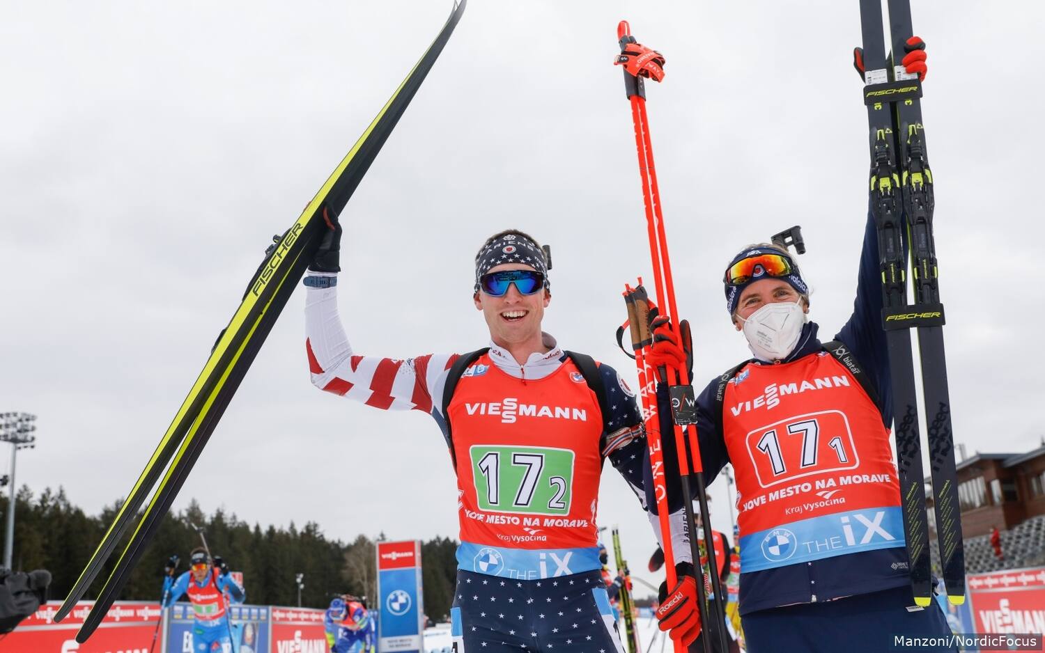 Sean Doherty and Susan Dunklee raise their arms in triumph as they are announced as bronze medalists in the single mixed relay