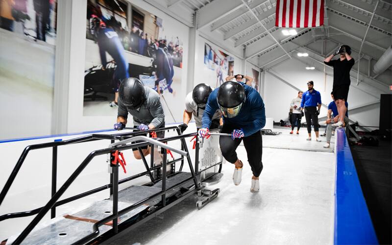 Athletes pushing a bobsled off at the start in the ice house