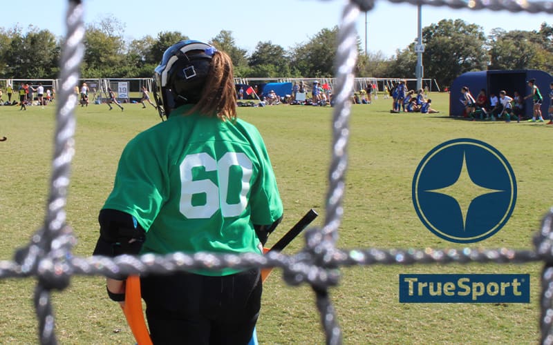 Field hockey goalkeeper standing in the goal at the National Hockey Festival with the TrueSport logo