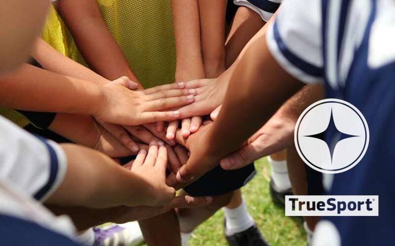 Team huddle with the hands in and TrueSport logo