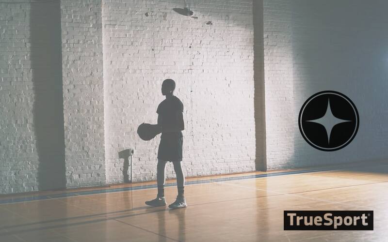 Siilouette of Man holding basketball in poorly lit gymnasium. Heavily shadowed