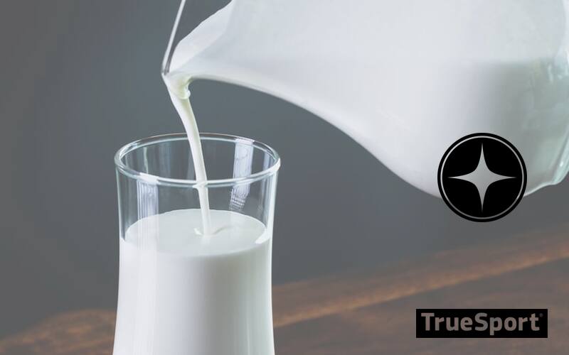 Pitcher of Milk Pouring into Glass, with a black background 