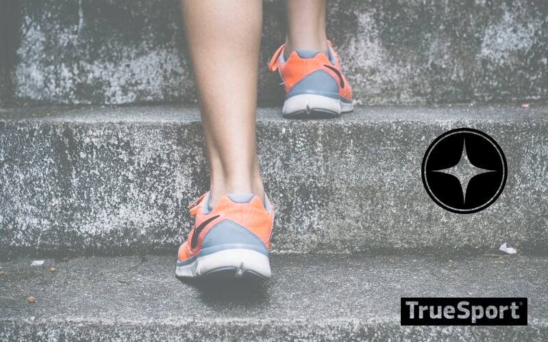 Person Wearing Sneakers Walking up Stone Stairs, the sneakers are grey with orange designs going around them