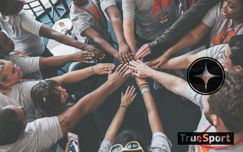Athletes in Huddle with all hands stretched to the middle