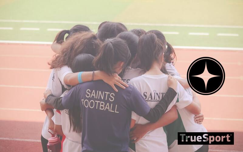 Athlete Huddle on Track, Athletes wearing white and black "Saints Football" jerseys 