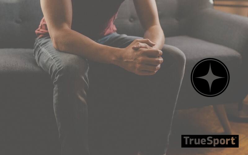 Man sitting on grey couch clasping hands together