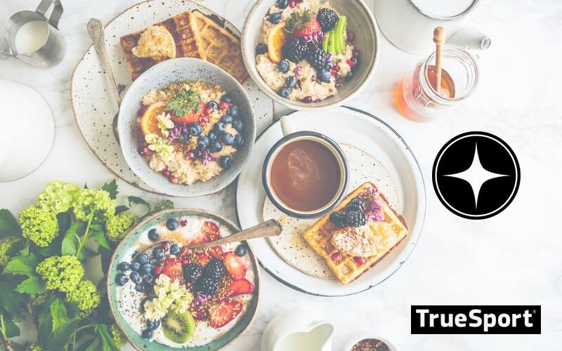 Assorted Breakfast Foods plated and arranged neatly on table. Including Fruit bowl, toast and morning oats
