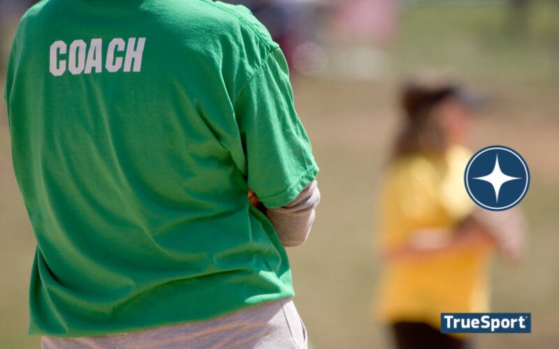 Back of a person with a green shirt that says the word Coach on the shirt