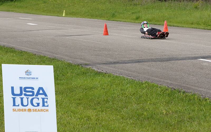 A young child on a wheeled luge sled 