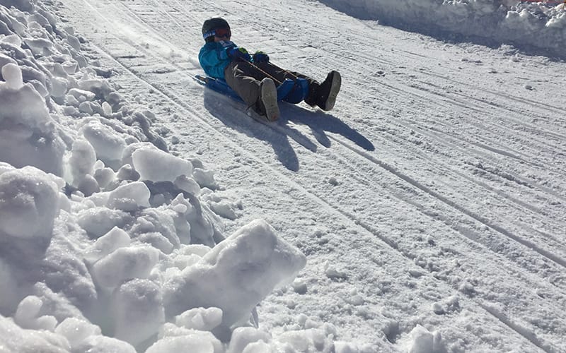 a young child riding a plastic luge sled