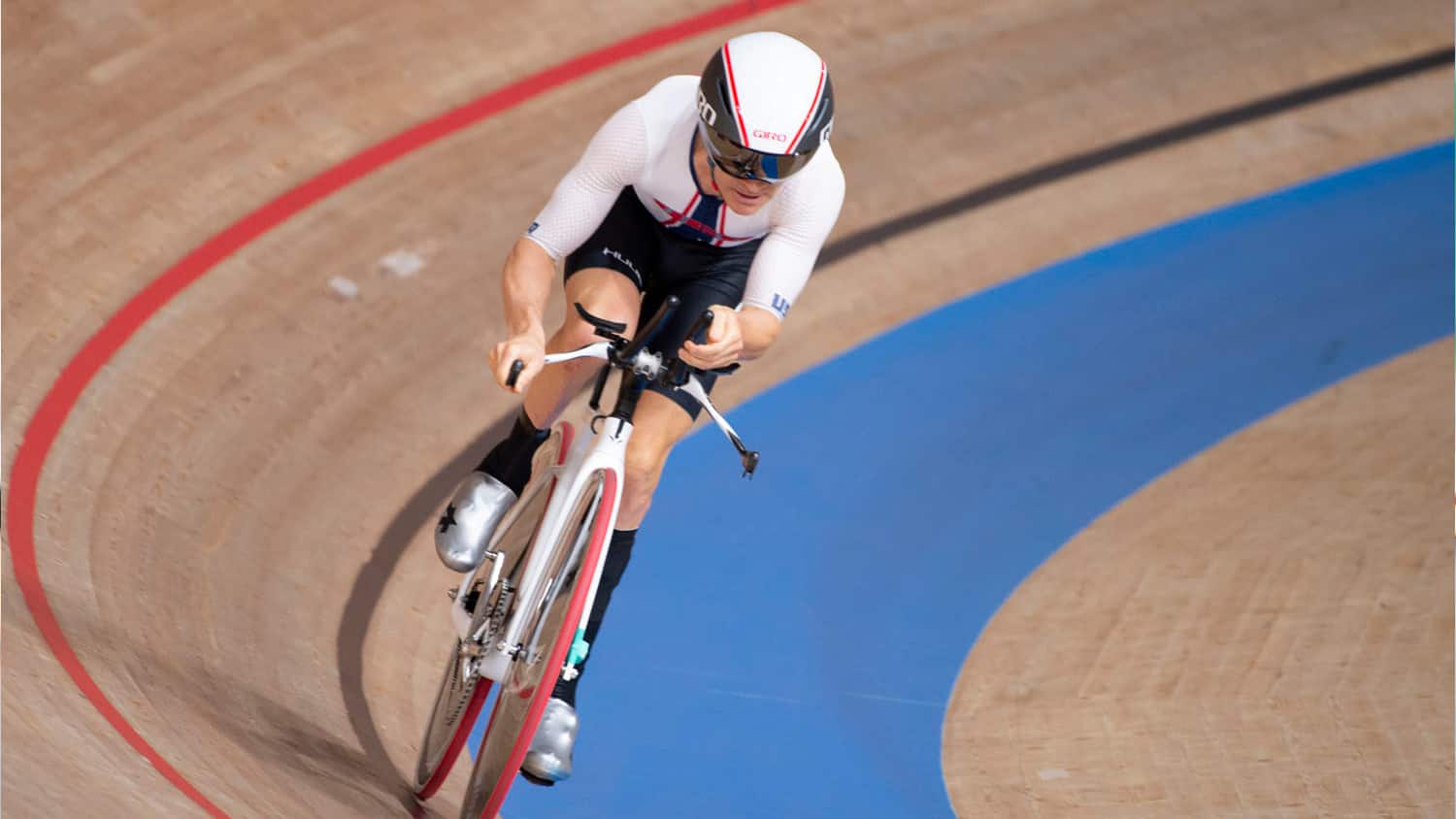 Aaron Keith rides a black bike on the track while wearing a white Team USA uniform and black helmet