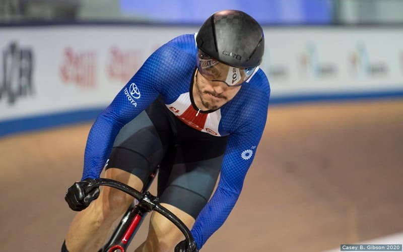 Chris Murphy races around the track, setting a world record in the flying 200. He is wearing Team USA colors and uniform while riding his bike. 