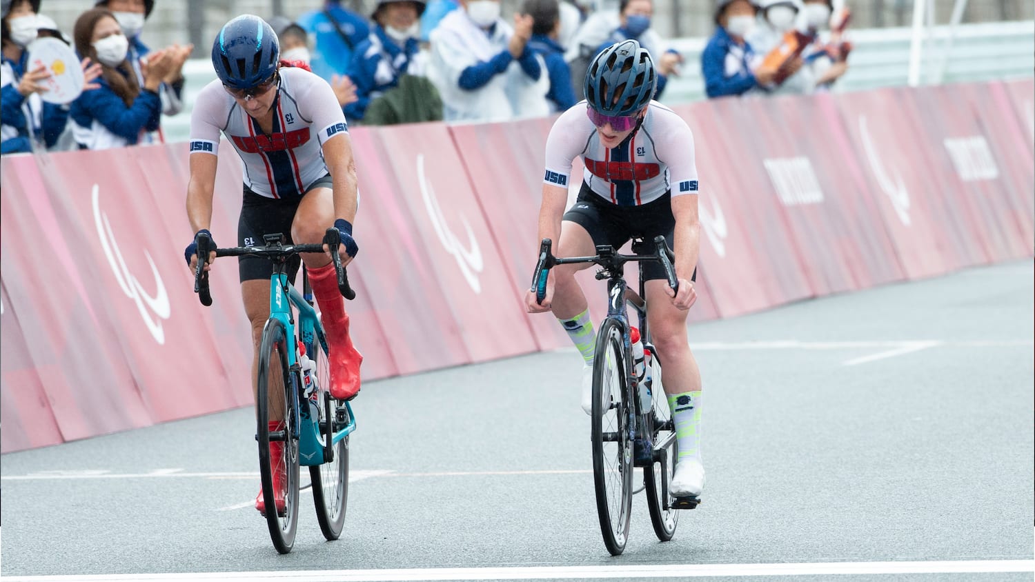 Jamie Whitmore and Clara Brown ride bikes across the finishline