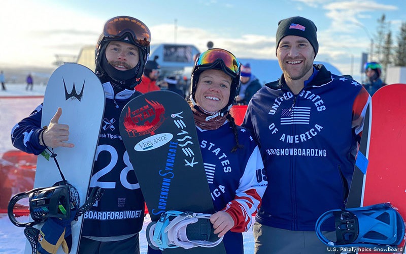 Three athletes smile for camera holding snowboards. 