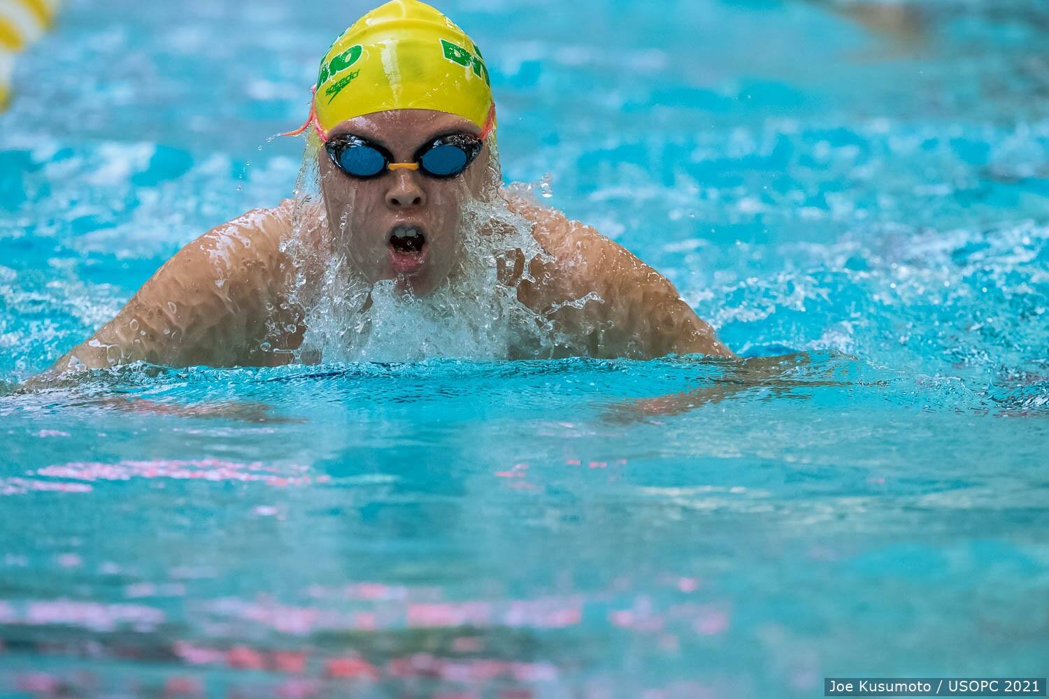 Gia Pergolini swims to a record in the pool wearing a yellow swim cap and goggles