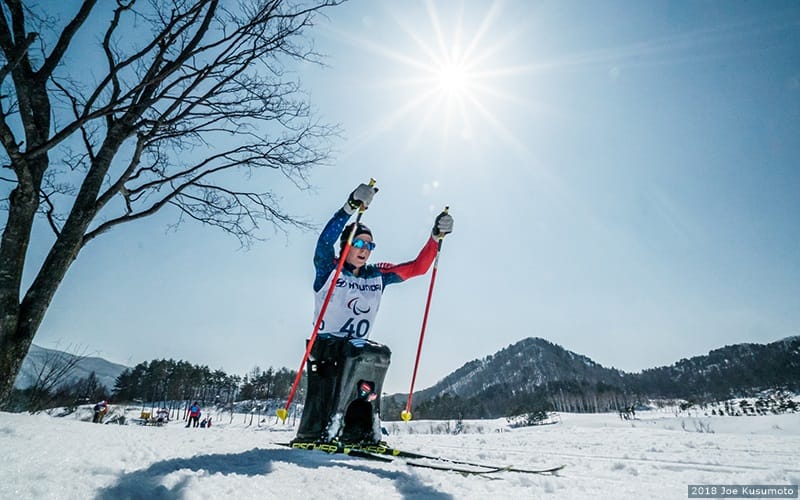 Woman competes in sitting nordic skiing class. 