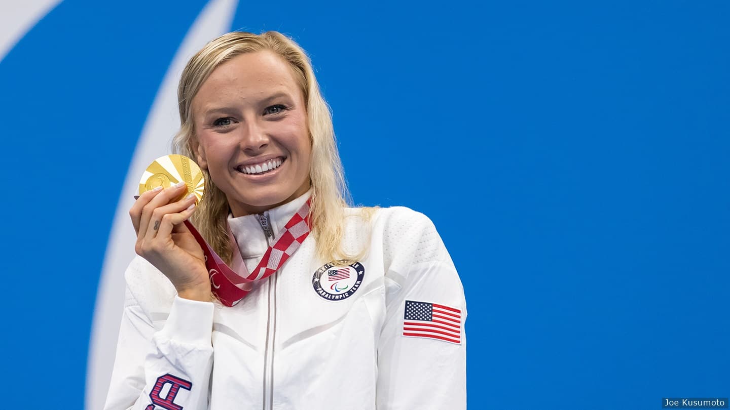 Jessica Long smiles for camera holding gold medal. 