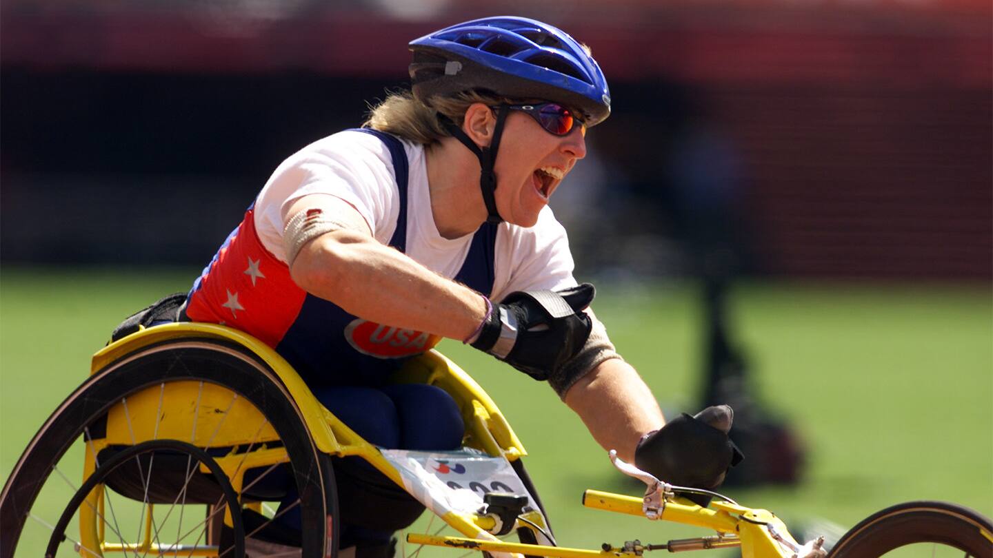 Athlete cheers after finish line in wheelchair racing competition. 