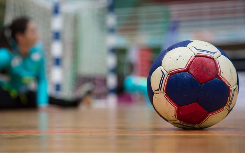 Handball on the court next to a player warming up