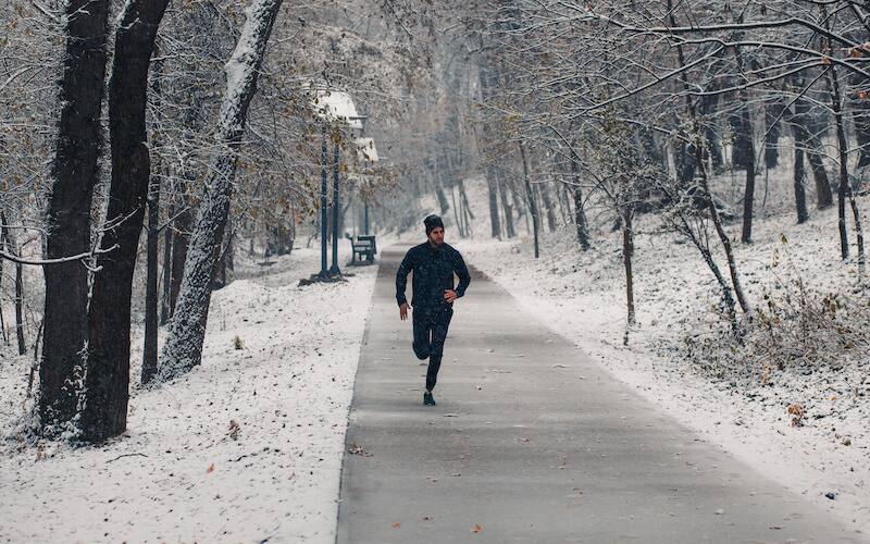 man running on park path in snow