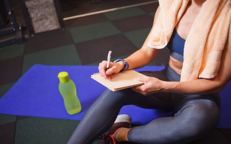 athlete sitting on mat and writing goals in notebook