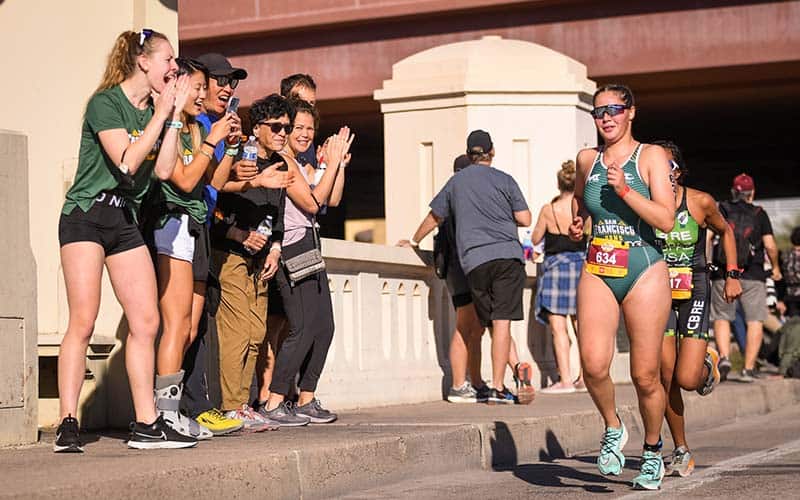 Athlete from University of San Francisco runs in front of cheering crowd in Tempe