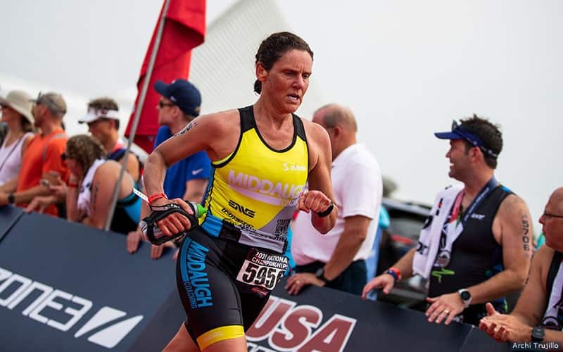 woman wearing a yellow race kit sprints down the finish line at age group national championships in milwaukee, wisconsin in august 2021.