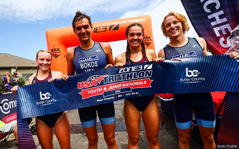 four teenaged triathletes pose together for a photo while holding the finishing tape from the mixed relay at youth and junior nationals in west chester ohio