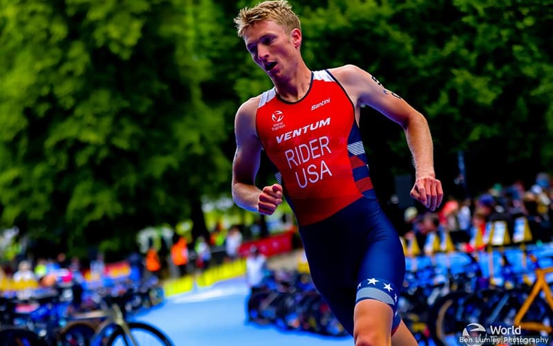 u.s. elite triathlete seth rider runs through the transition area during the mixed relay at leeds, england. he is wearing a red jersey with his name Rider across his chest