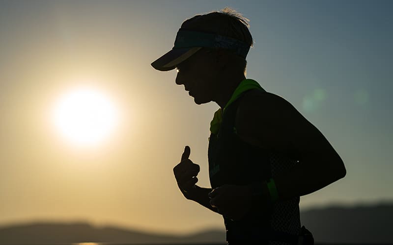 a runner runs with the sun rising behind them