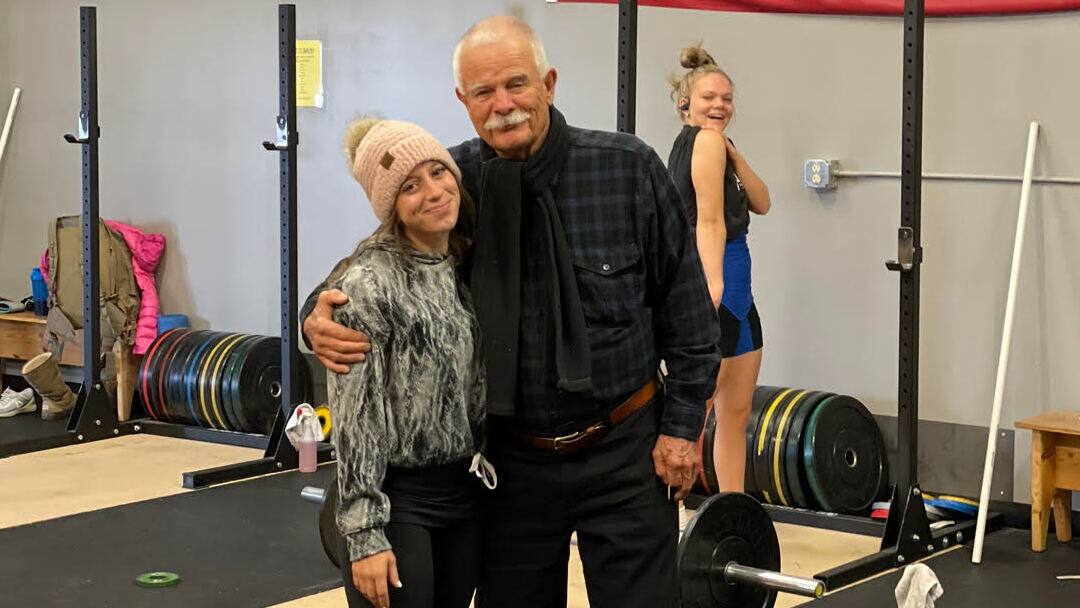 Kathleen Winters and coach Steve Gough pose for a photo in a gym