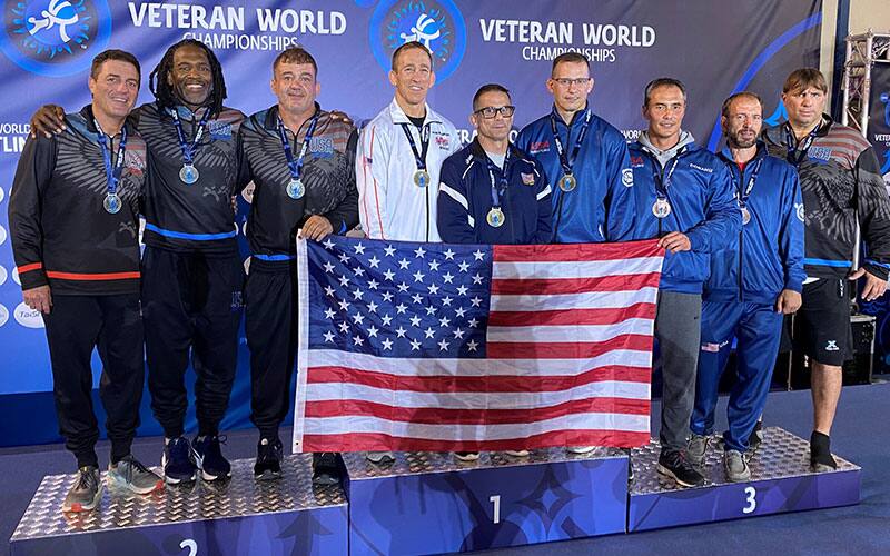 The nine U.S. Veterans wrestlers who won freestyle medals on October 20, 2021 pose together with the U.S. flag