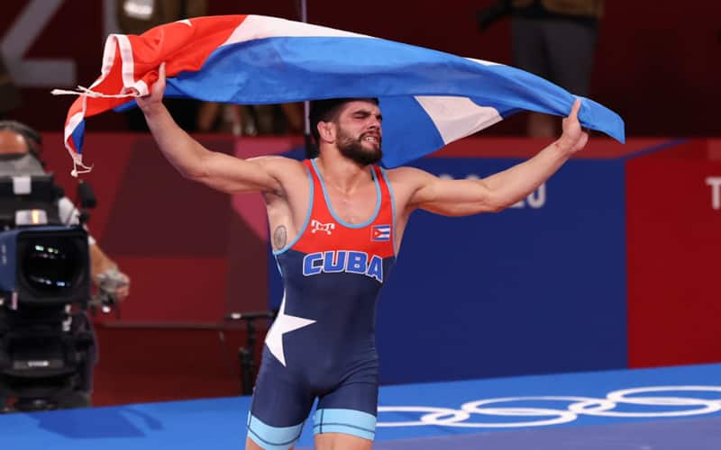 Olympic champion Luis Orta of Cuba carries the Cuban flag on center mat
