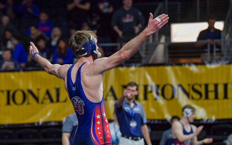 Liberty University wrestler raises his arms to the crowd at the 2022 NCWA Nationals